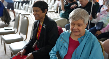 Two NFB of Illinois members smile together at the Ride for Literacy celebration.